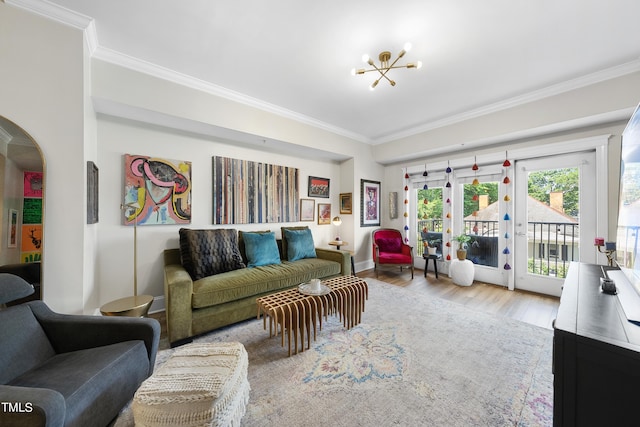 living room with a notable chandelier, ornamental molding, and light wood-type flooring