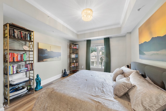 bedroom featuring ornamental molding, a tray ceiling, and light hardwood / wood-style floors