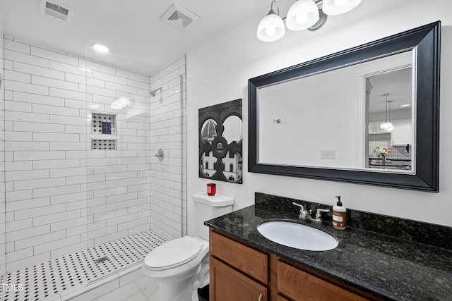 bathroom featuring tiled shower, vanity, tile patterned flooring, and toilet