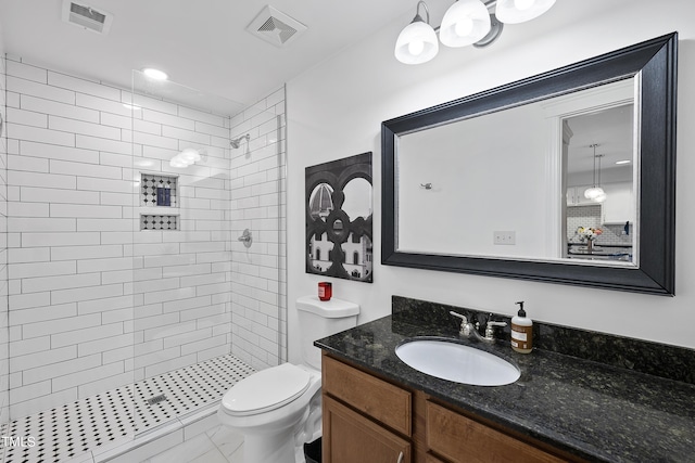 bathroom featuring vanity, toilet, and tiled shower