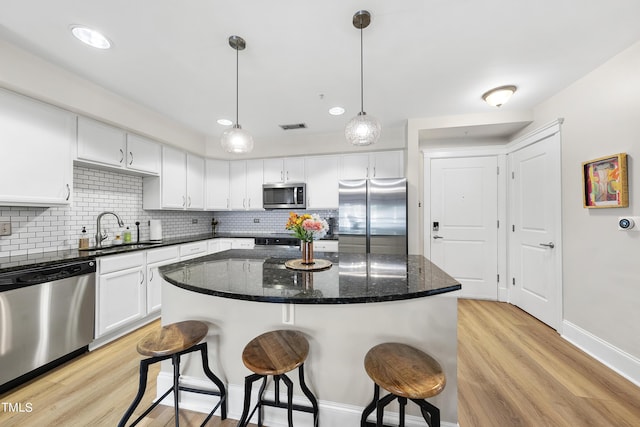 kitchen with hanging light fixtures, appliances with stainless steel finishes, sink, and white cabinets