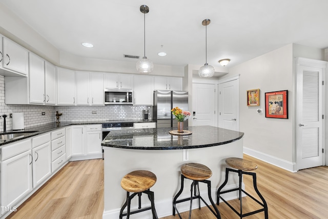 kitchen featuring pendant lighting, white cabinetry, stainless steel appliances, and a kitchen island