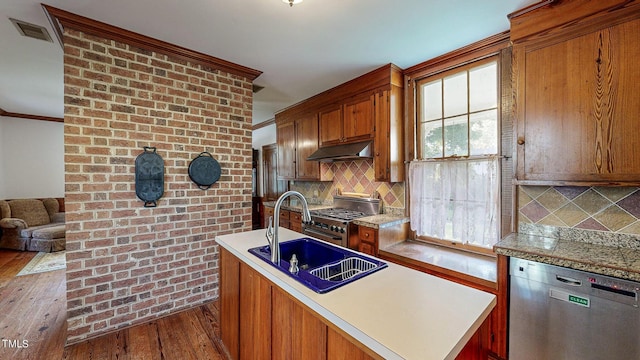 kitchen with brown cabinets, stainless steel appliances, light countertops, a sink, and under cabinet range hood