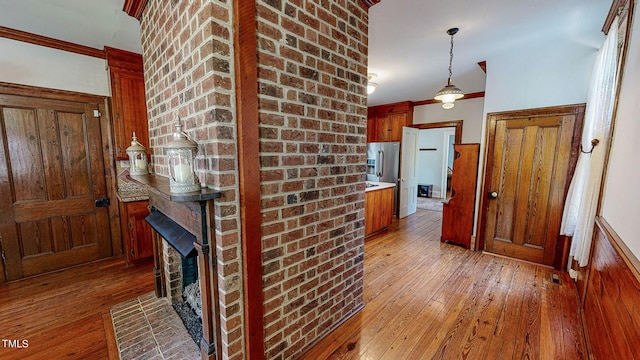 kitchen with light wood finished floors, light countertops, hanging light fixtures, and ornamental molding