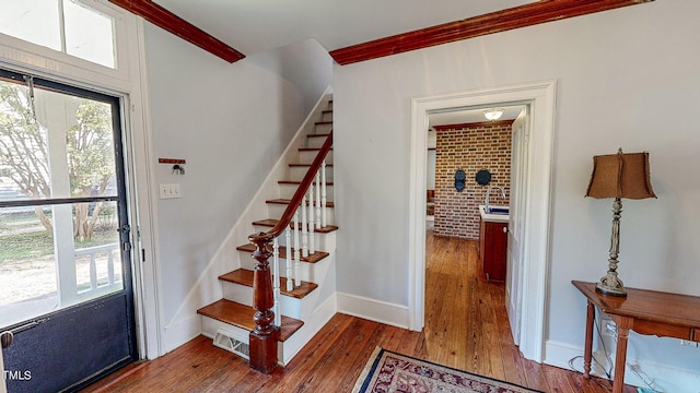 entrance foyer featuring visible vents, baseboards, brick wall, stairway, and dark wood-type flooring