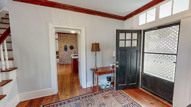 foyer featuring baseboards, stairway, wood finished floors, and crown molding