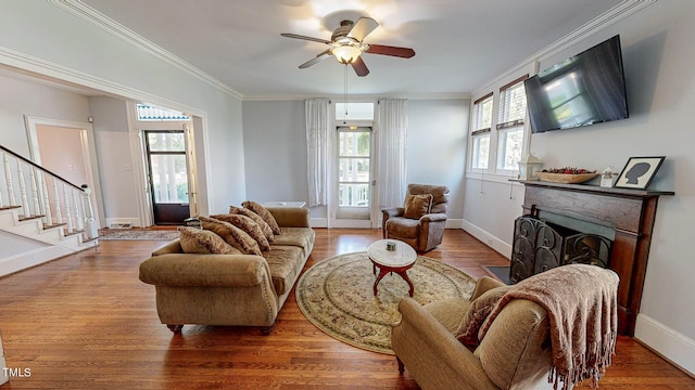 living room with a fireplace, baseboards, crown molding, and wood finished floors