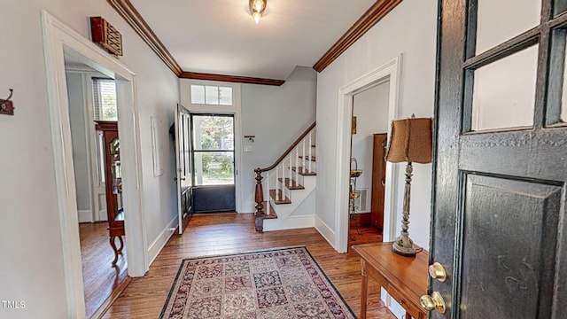 foyer with crown molding, stairway, baseboards, and wood finished floors