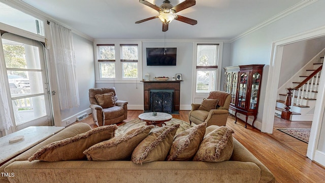 living area featuring stairway, a fireplace, light wood-style flooring, and ornamental molding