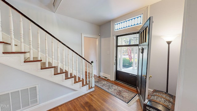 foyer featuring baseboards, stairs, visible vents, and wood finished floors