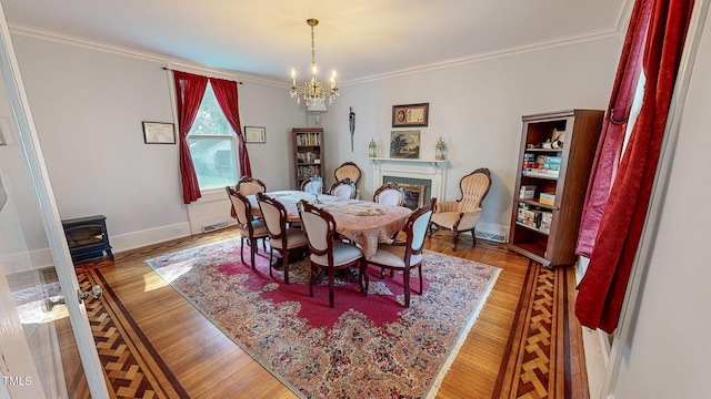 dining area with a chandelier, crown molding, and wood finished floors