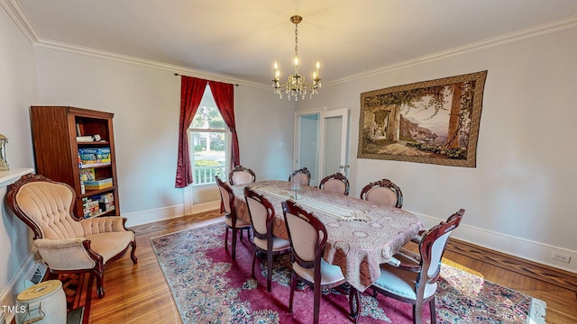 dining room with crown molding, a notable chandelier, baseboards, and wood finished floors