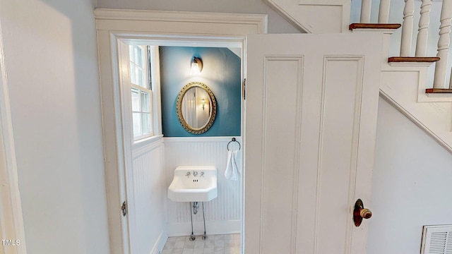 bathroom with a wainscoted wall and visible vents