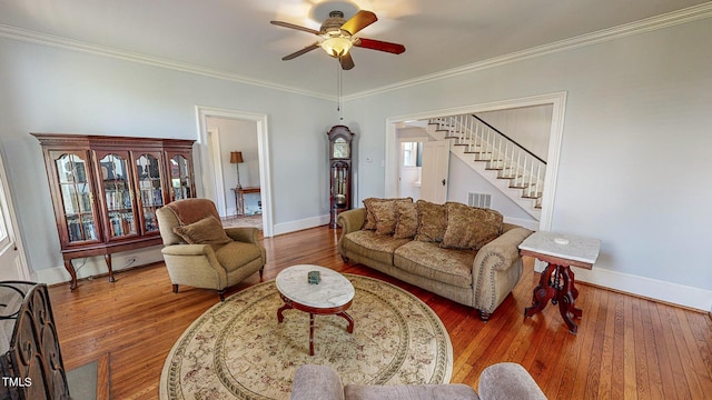 living room featuring stairs, ornamental molding, baseboards, and wood finished floors