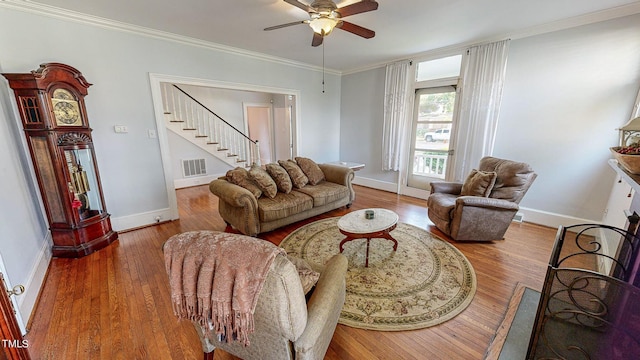 living area featuring ornamental molding, visible vents, stairway, and wood finished floors