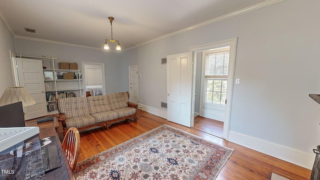 living room featuring baseboards, crown molding, visible vents, and wood finished floors