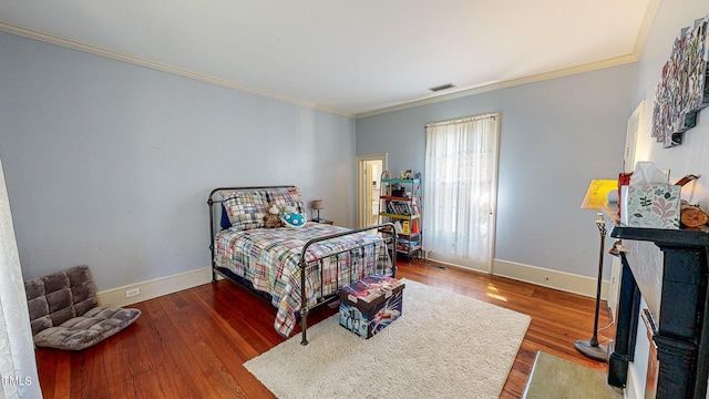 bedroom featuring a fireplace, crown molding, visible vents, wood finished floors, and baseboards