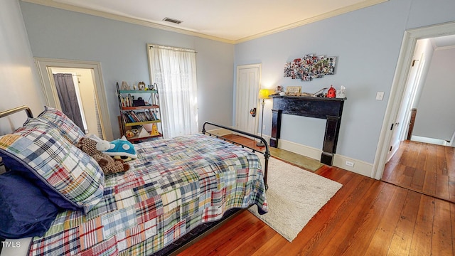 bedroom featuring baseboards, visible vents, ornamental molding, and wood finished floors