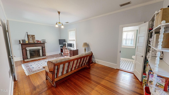 living room featuring crown molding, visible vents, wood finished floors, and a fireplace with flush hearth