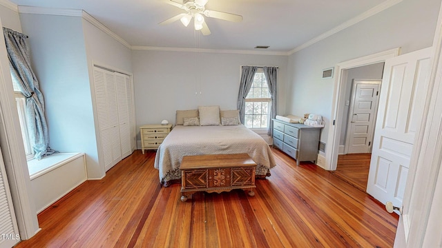 bedroom with visible vents, crown molding, and wood finished floors