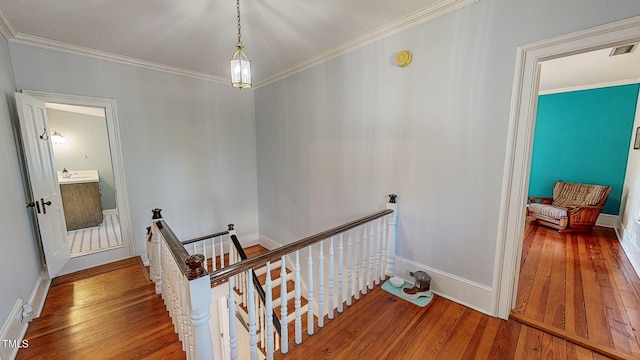 corridor featuring ornamental molding, wood finished floors, and an upstairs landing