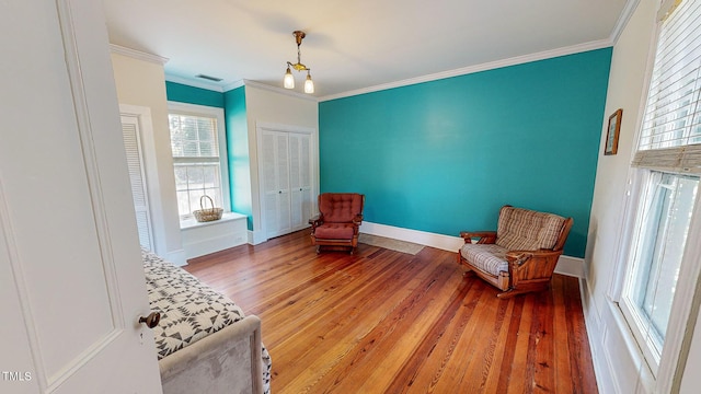 sitting room with wood finished floors, visible vents, and crown molding