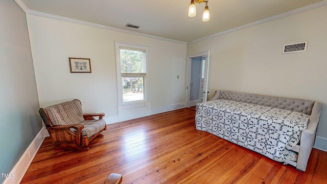 bedroom with ornamental molding, visible vents, baseboards, and wood finished floors