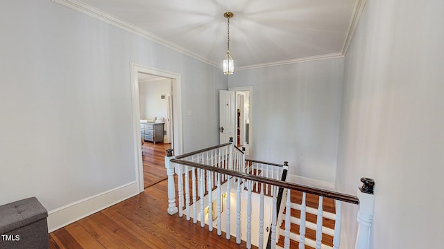 hallway featuring ornamental molding, baseboards, an upstairs landing, and wood finished floors