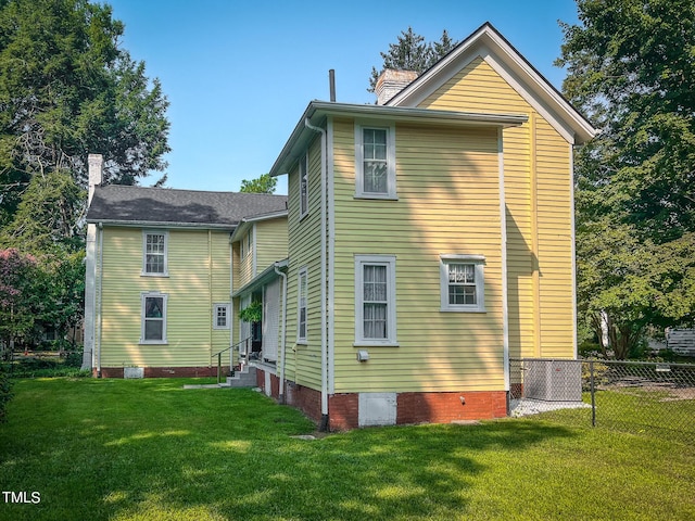 rear view of property with a chimney, a lawn, entry steps, fence, and cooling unit