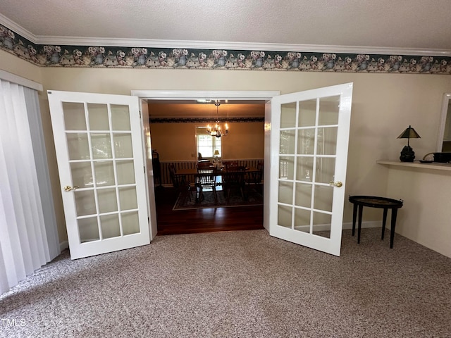 unfurnished dining area featuring french doors, ornamental molding, a chandelier, and a textured ceiling