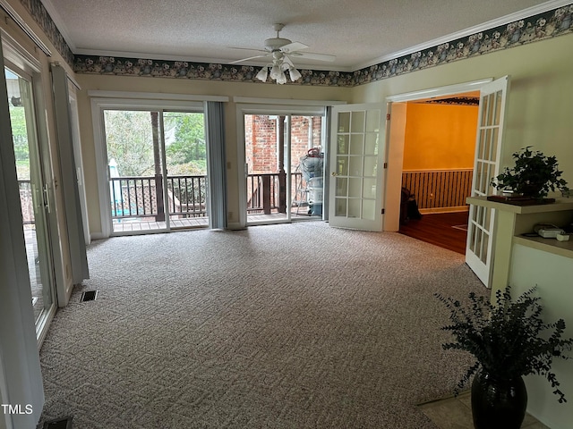 carpeted spare room featuring crown molding, ceiling fan, and a textured ceiling