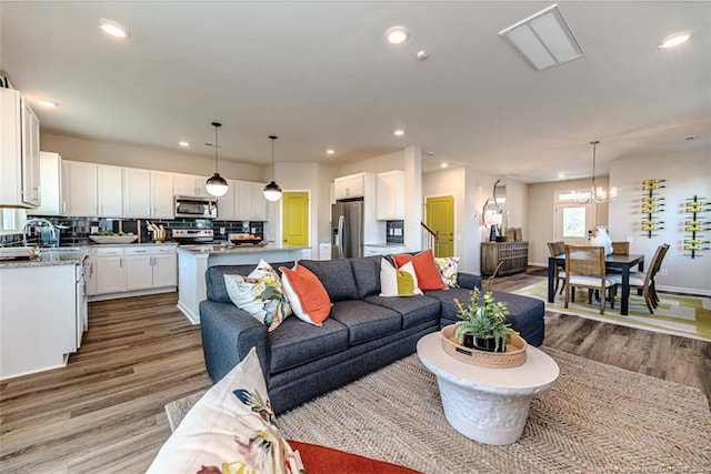 living room with hardwood / wood-style flooring, a chandelier, and sink