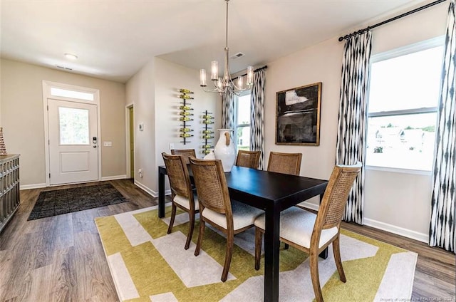 dining space featuring wood-type flooring and a chandelier