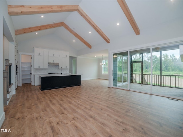 16 Autumn Breeze Ct, Angier, NC 27501 - unfurnished living room with high vaulted ceiling, beam ceiling, light wood-style floors, a chandelier, and baseboards