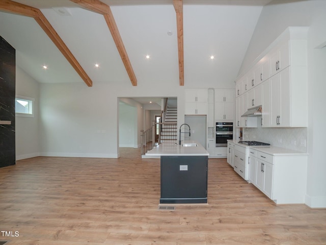 16 Autumn Breeze Ct, Angier, NC 27501 - kitchen featuring under cabinet range hood, double oven, open floor plan, baseboards, and a center island with sink
