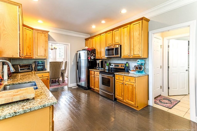 kitchen featuring sink, appliances with stainless steel finishes, light stone counters, ornamental molding, and dark hardwood / wood-style flooring