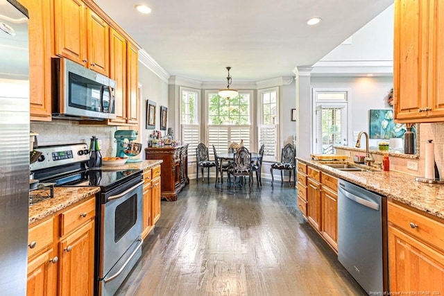 kitchen with sink, crown molding, hanging light fixtures, appliances with stainless steel finishes, and light stone countertops