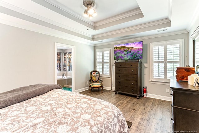 bedroom with hardwood / wood-style flooring, ensuite bathroom, crown molding, and a raised ceiling