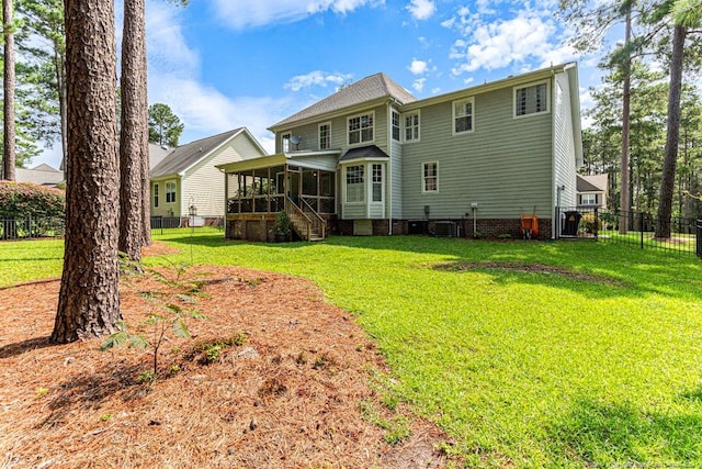 rear view of house featuring a lawn and a sunroom