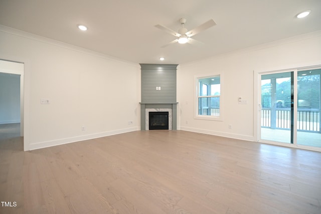 unfurnished living room featuring a large fireplace, ceiling fan, light hardwood / wood-style floors, and crown molding