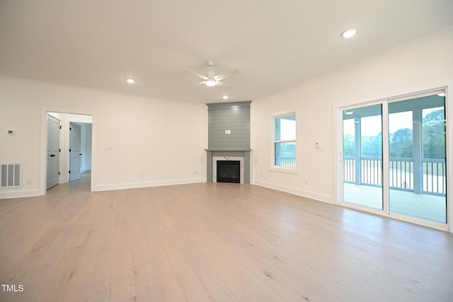 unfurnished living room with light wood-type flooring, a large fireplace, a wealth of natural light, and ceiling fan