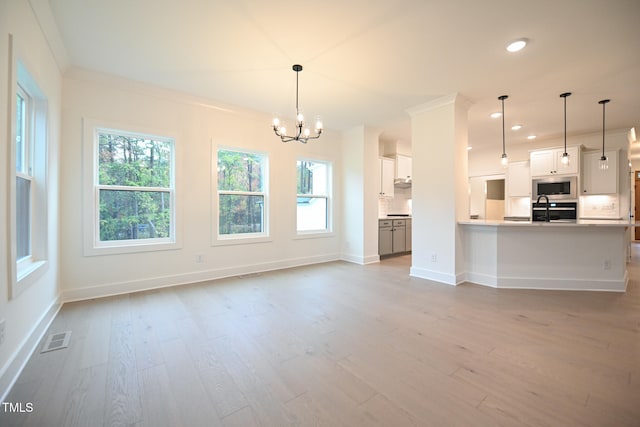 unfurnished living room featuring crown molding, light hardwood / wood-style flooring, a chandelier, and sink