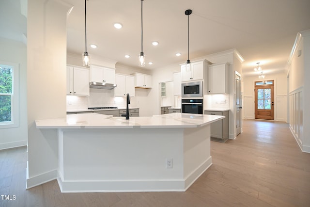 kitchen with white cabinets, decorative light fixtures, stainless steel appliances, and a wealth of natural light