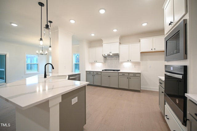 kitchen featuring sink, black appliances, decorative light fixtures, and light hardwood / wood-style flooring