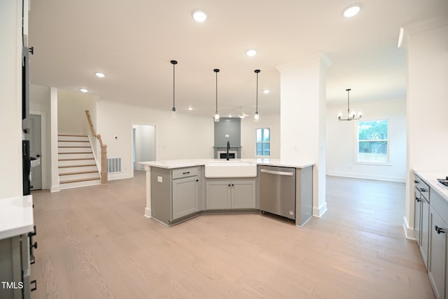 kitchen with gray cabinets, hanging light fixtures, stainless steel dishwasher, and light wood-type flooring