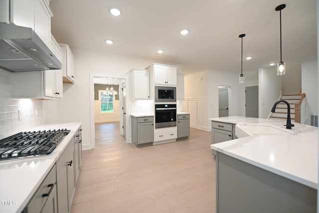 kitchen with gray cabinetry, pendant lighting, backsplash, appliances with stainless steel finishes, and extractor fan