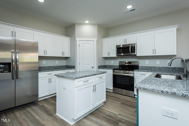 kitchen with visible vents, dark wood-style flooring, stainless steel appliances, white cabinetry, and a sink