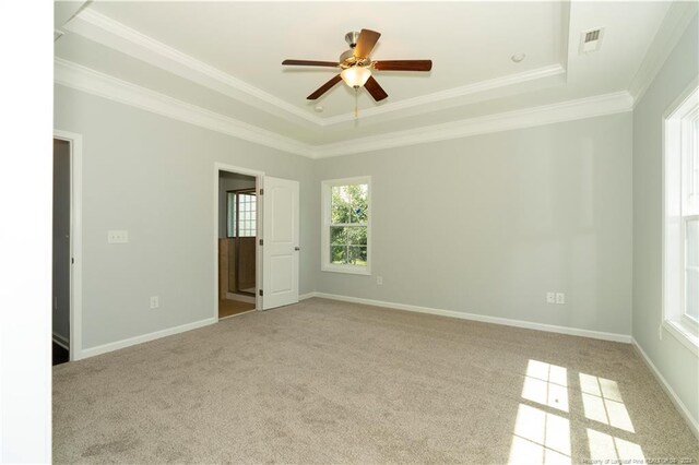 unfurnished bedroom with ceiling fan, crown molding, light carpet, and a tray ceiling