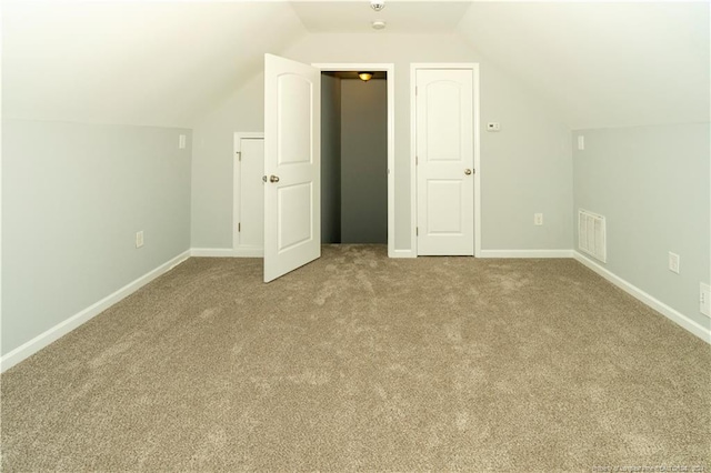 additional living space featuring light colored carpet and vaulted ceiling