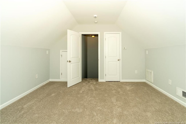 bonus room with lofted ceiling and light colored carpet